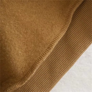 Macro shot of brown fleece fabric with ribbed knit cuff detail and neat stitching seams