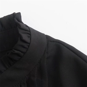 Dettaglio della camicia nera a maniche lunghe con collo a volant e trama del tessuto