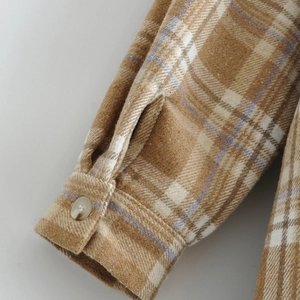 Primer plano del puño de camisa de franela a cuadros con botón y textura suave