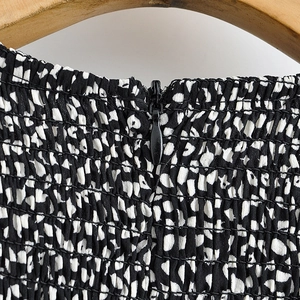 Macro detail of smocked polka dot fabric with an invisible black zipper on a wood hanger