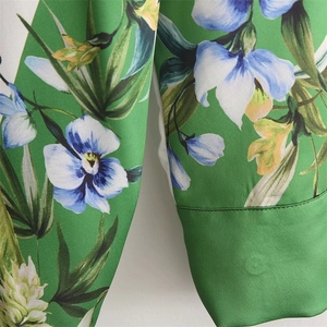 Detailed close-up of vibrant floral print on premium green satin fabric with fine stitching