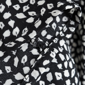 Close-up of black and white leaf print fabric with detailed stitching on the long dress
