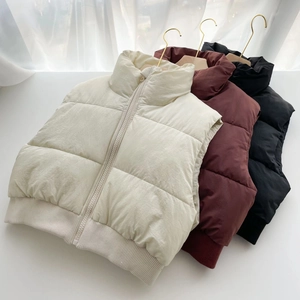Détail de gilets matelassés à col montant en beige, bordeaux et noir avec ourlet côtelé