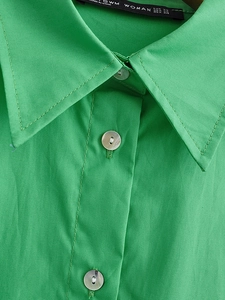 Detail shot of a bright green cotton poplin shirt collar with white pearlized buttons