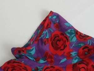 Détail macro du tissu floral violet avec roses rouges et finitions de couture qualité