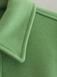 Macro detail of grass green wool blend jacket featuring lapel with fine topstitch