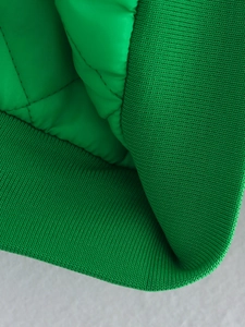 Detail shot of bright green quilted jacket featuring textured ribbed cuffs and fabric