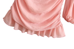 Detail of pink chiffon top featuring layered ruffles and pleated hemline on white background