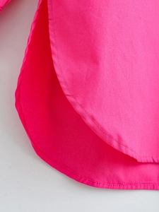 Detailed close-up of the curved hem and side slit of the fuchsia cotton poplin shirt