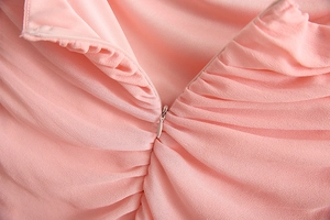 Close-up of invisible teardrop zipper and pleated chiffon texture on a pink dress