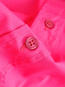 Macro shot of hot pink poplin shirt showing matching buttons and neat stitching detail
