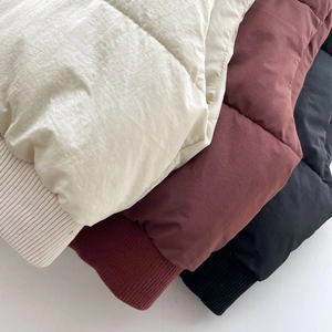 Vue détaillée de gilets matelassés avec poignets côtelés en beige, bordeaux et noir