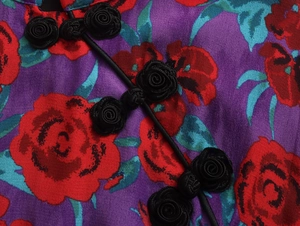 Détail de robe fleurie violette avec bouton traditionnel rose noire et tissu en soie
