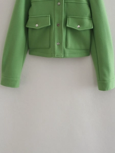 Detailed view of the bright green wool blend jacket featuring metal buttons and pockets