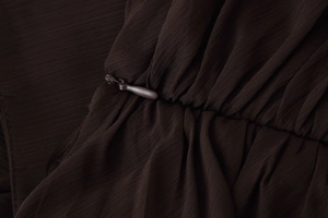 Macro detail of hidden zipper and pleated texture on brown high-waist summer skirt