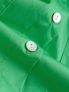 Detailed macro view of bright green poplin shirt fabric with premium white buttons