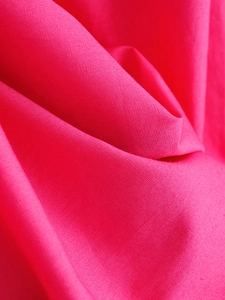 Macro shot of rose pink poplin fabric texture showing fine weave and premium density