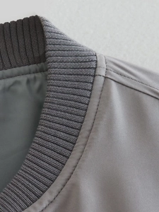 Detailed close-up of ribbed collar and stitching on grey Y2K bomber jacket fabric