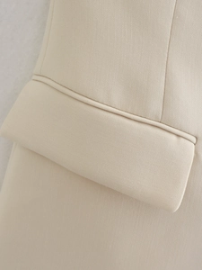 Detailed close-up of a flap pocket on a beige tailored vest with precise stitching