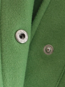Close-up of metal snap buttons on green soft lapel jacket showing fabric texture