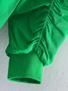 Detailed close-up of green jacket sleeve featuring ruched texture and ribbed cuffs