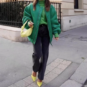 Detail of a bright green quilted bomber jacket with zip-up design and ribbed cuffs