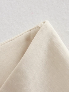 Detailed macro shot showing twill fabric texture and clear hanging strap on cream vest