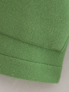 Close-up of green wool blend coat featuring stitching details and pocket flap design