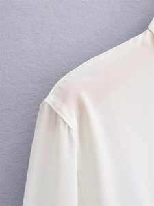 Close-up of shoulder stitching and sheer fabric texture on a white long sleeve shirt
