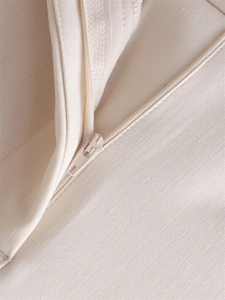 Detailed macro view of the matching beige zipper and fine stitching on high waist trousers
