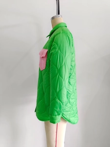 Detail of green quilted jacket featuring a contrasting pink flap pocket and diamond stitching
