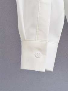 Detailed close-up of a white long-sleeve shirt cuff with button and clean stitching