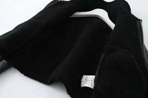 Detail einer schwarzen Kunstlederjacke mit warmem Sherpa-Futter und silbernem Reißverschluss