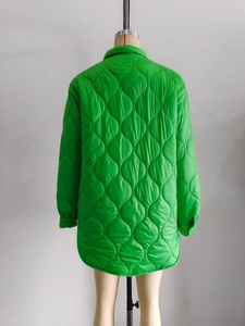 Detail view of bright green quilted jacket featuring wavy patterns and a curved hemline