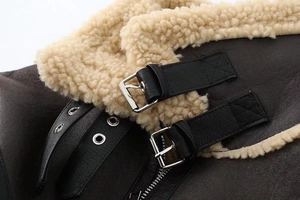 Macro detail of faux suede jacket featuring cream faux fur collar and metal buckle straps