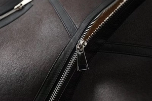 Close-up of premium pebbled leather texture and high-gloss silver metal zippers