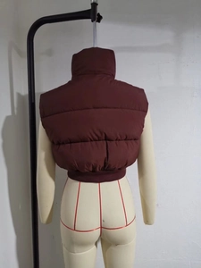 Rear view of cropped burgundy puffer vest with high collar and ribbed elastic hemline