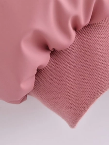 Detail view of pink faux leather jacket showing soft fabric and ribbed knit cuffs