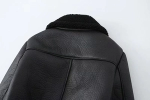 Detail der schwarzen Kunstlederjacke mit Plüschkragen und präzisen Nähten am Rücken