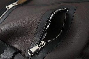 Detailed macro view of silver metal zipper and textured faux leather pocket stitching