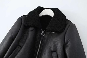 Nahaufnahme der schwarzen Kunstlederjacke mit Lammfellkragen und Metallring-Reißverschluss