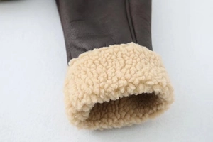Detail of dark brown leather jacket cuff with thick beige shearling lining and texture