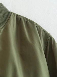 Detailed close-up of ribbed collar and pleated shoulder seams on army green flight jacket