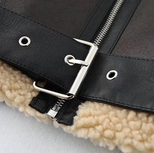 Detail of leather shearling jacket showing metal buckle strap and soft fleece texture