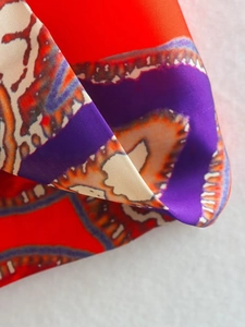 Détail du pantalon taille haute montrant l'imprimé abstrait sur un tissu soyeux et lisse