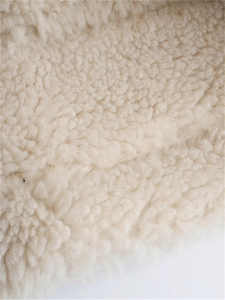 Macro shot of thick cream-colored faux fur lining with curly fiber texture for winter jacket