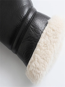 Detail of winter jacket showing black faux leather texture and thick fleece lining