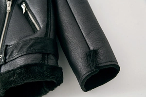 Detailaufnahme der schwarzen Bikerjacke mit Lederstruktur und dicken Kunstfellbündchen