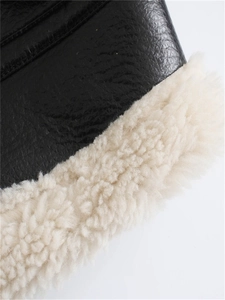 Close-up of black faux leather jacket texture with thick cream shearling fleece lining