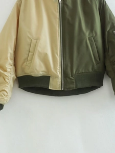 Detail of color-block bomber jacket with silver zipper and contrast ribbed cuffs
